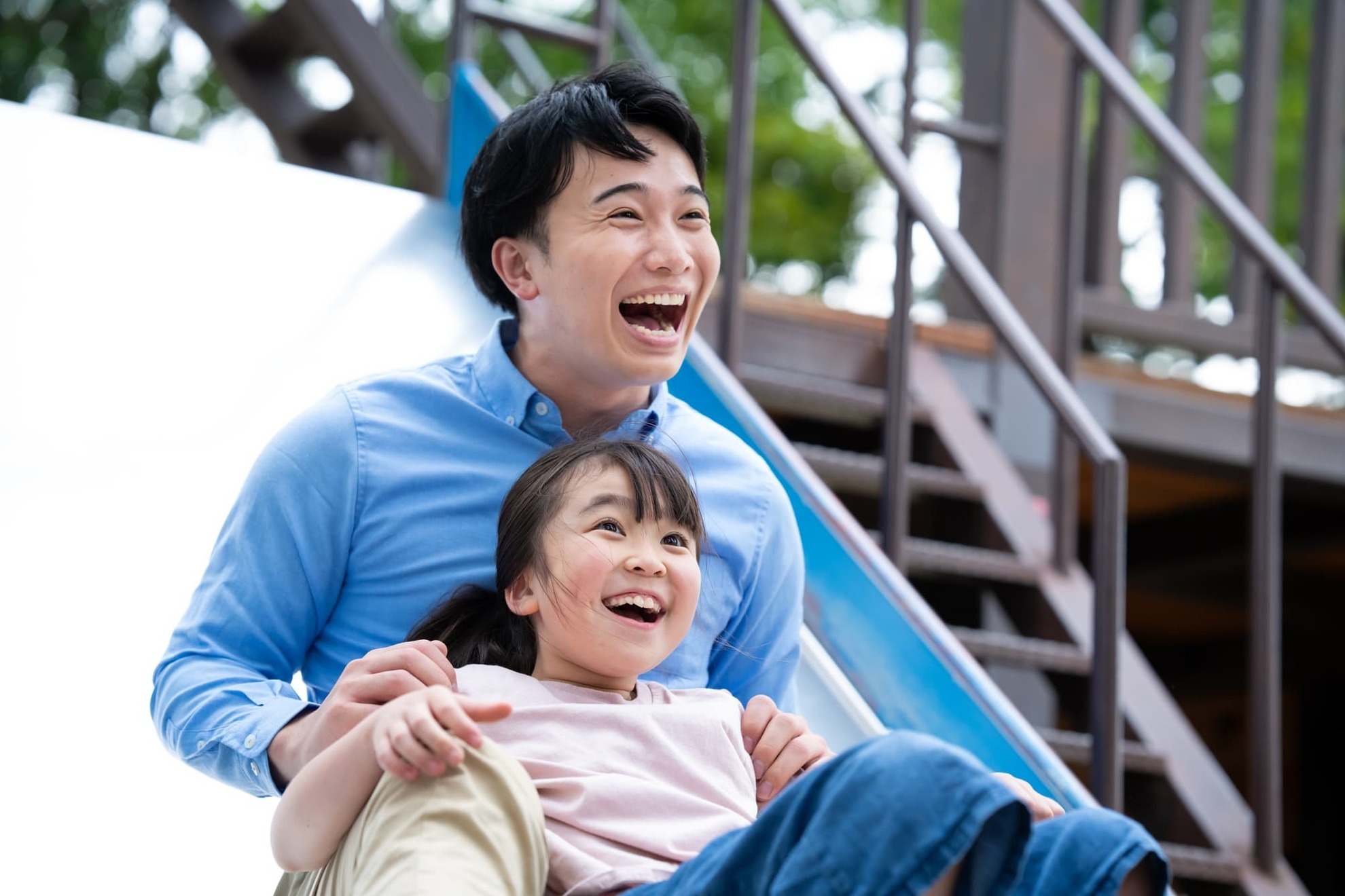 滑り台で楽しそうに遊ぶ父娘
