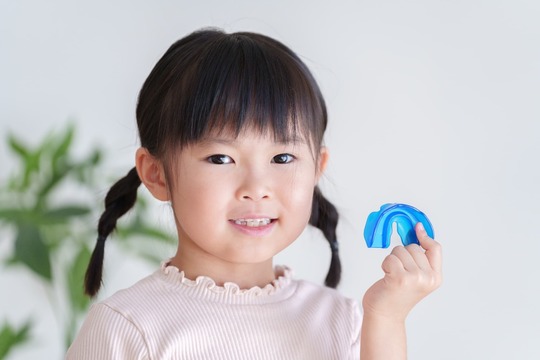 マウスピース矯正の装置を持って笑顔の女の子