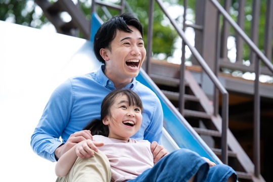 滑り台で楽しそうに遊ぶ父娘