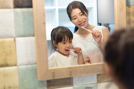 鏡を見ながら歯磨きする親子