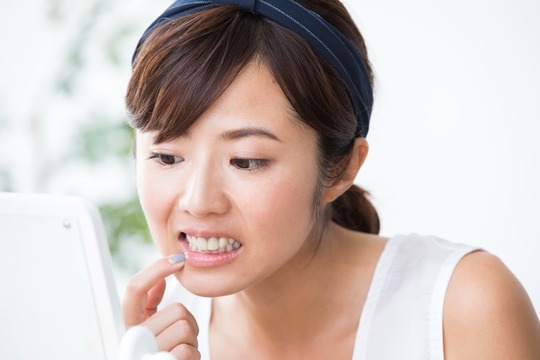 矯正後の歯並びの後戻りが気になって鏡を見る女性