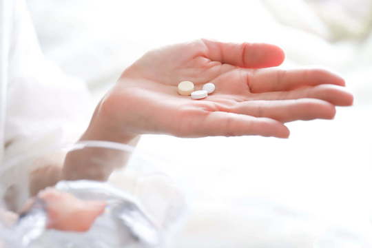 マウスピース矯正の痛みを和らげるため痛み止めを服薬する女性