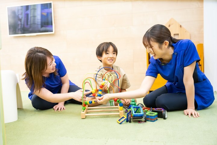 男の子と一緒に、おもちゃで遊ぶ保育士2人