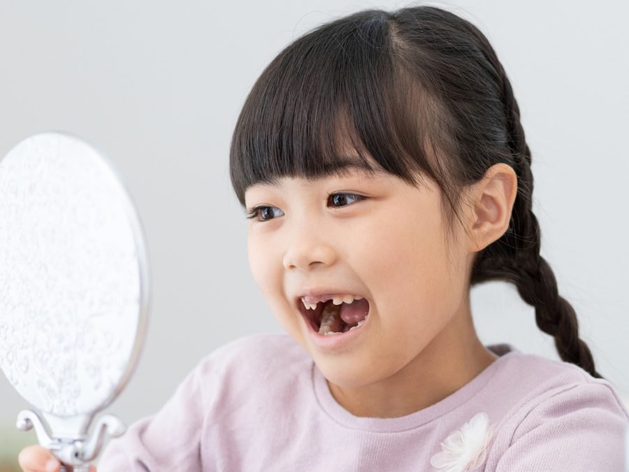 手鏡で自分の歯を見る女の子