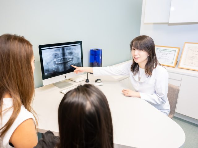 レントゲン画像を指しながら親子に説明する歯科医師